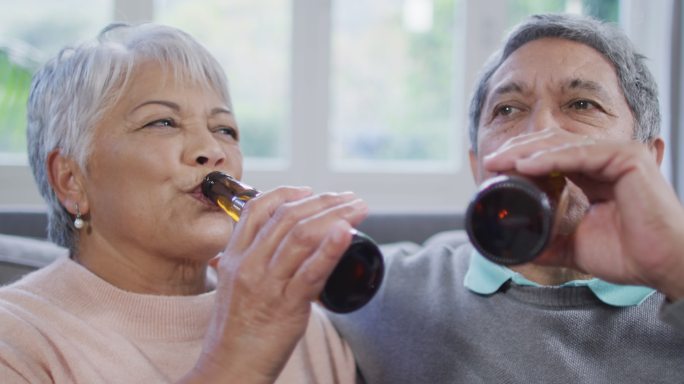 快乐的混血老年夫妇喝啤酒，玩得开心