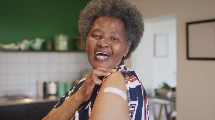 快乐的非洲裔美国老年妇女，手臂上的石膏在covid疫苗接种后