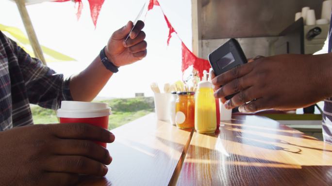非洲裔美国人在餐车用信用卡给男主人买咖啡