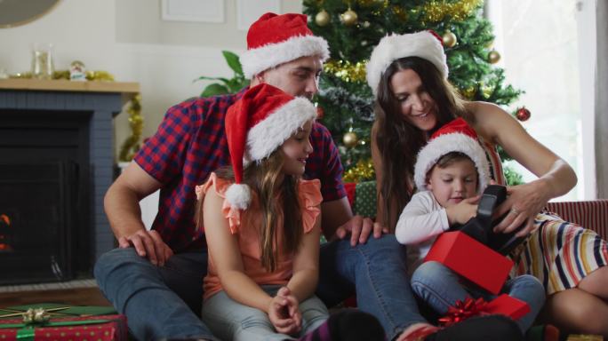 幸福的白种人家庭戴着圣诞帽拆礼物