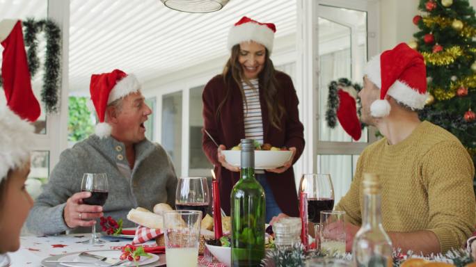 幸福的白种人多代家庭戴着圣诞帽，吃着圣诞大餐
