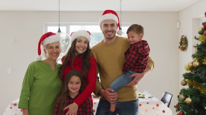 快乐的白种人多代家庭戴着圣诞帽，看着镜头