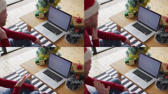 快乐的白化病非裔美国人戴着圣诞帽在圣诞节使用带拷贝空间的笔记本电脑