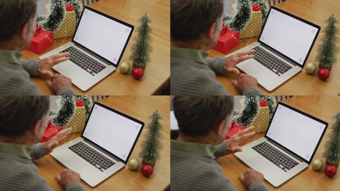 白人老人坐在桌子旁，用笔记本电脑在家里打视频电话，屏幕上有复印空间