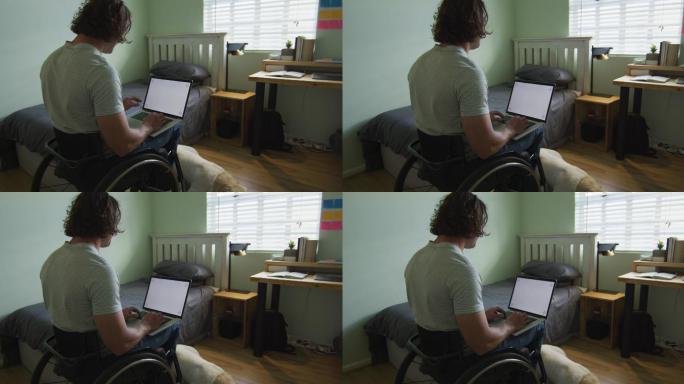 白人残疾人坐在轮椅上在卧室里使用笔记本电脑