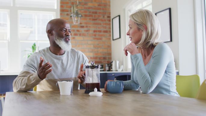 混合种族的老年夫妇在家里喝咖啡时互相交谈