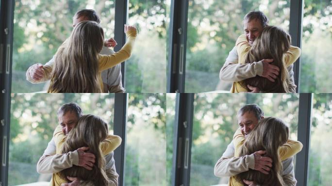 快乐的老年白人父亲和十几岁的女儿拥抱在窗口的花园景观
