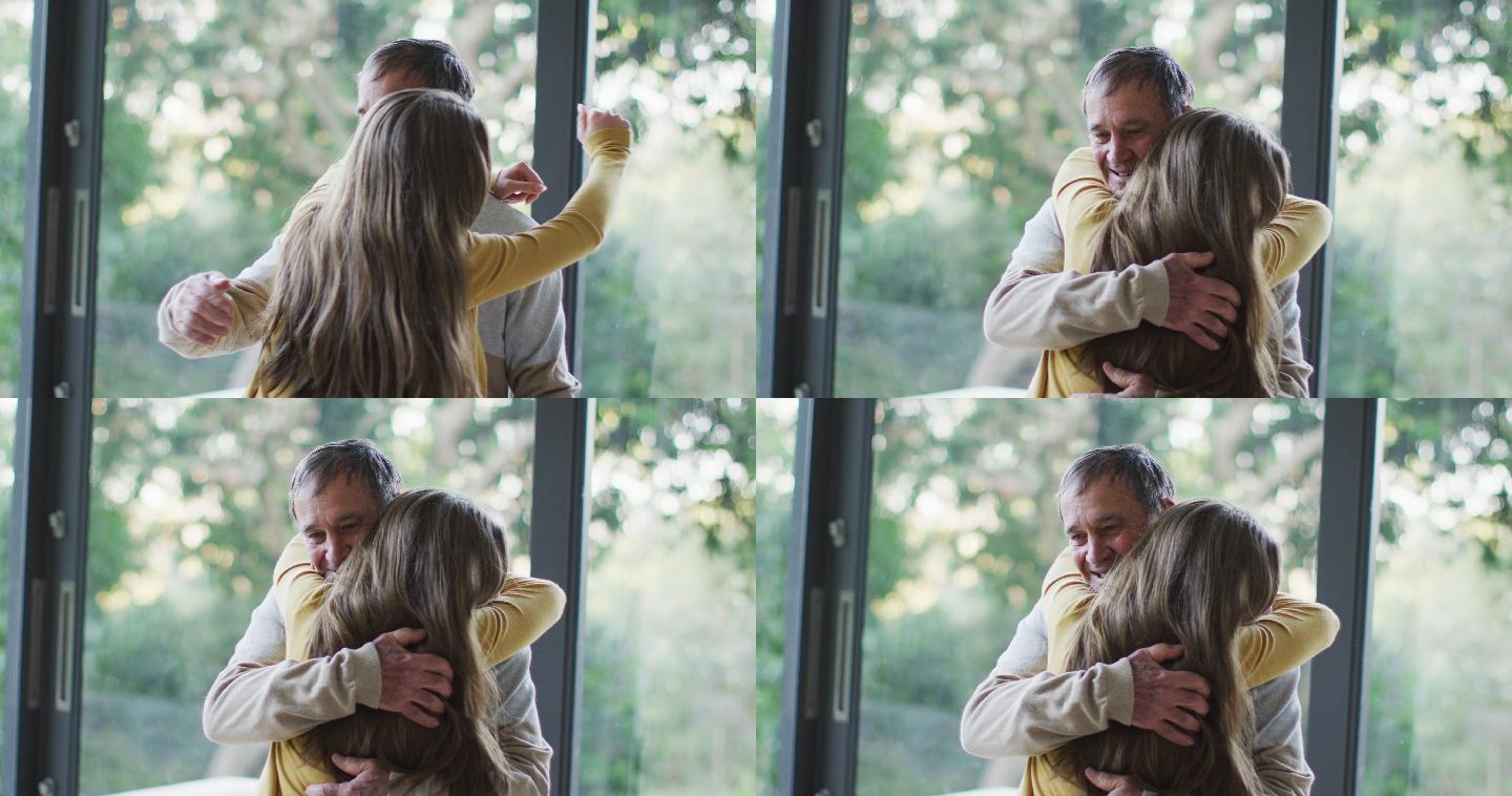 快乐的老年白人父亲和十几岁的女儿拥抱在窗口的花园景观
