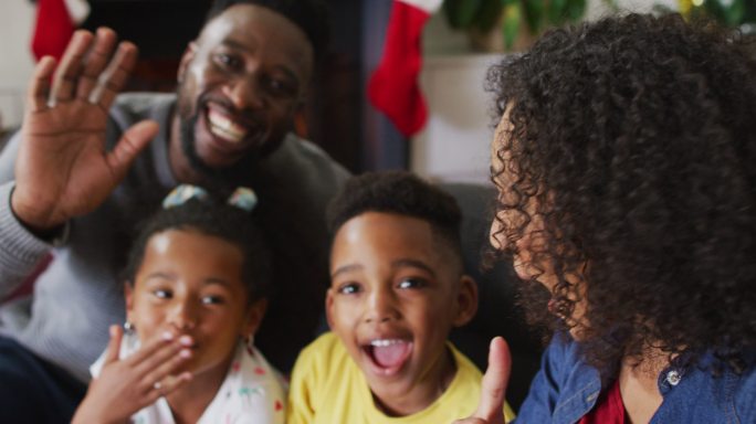 非洲裔美国家庭在视频通话中微笑着亲吻，背景是圣诞装饰