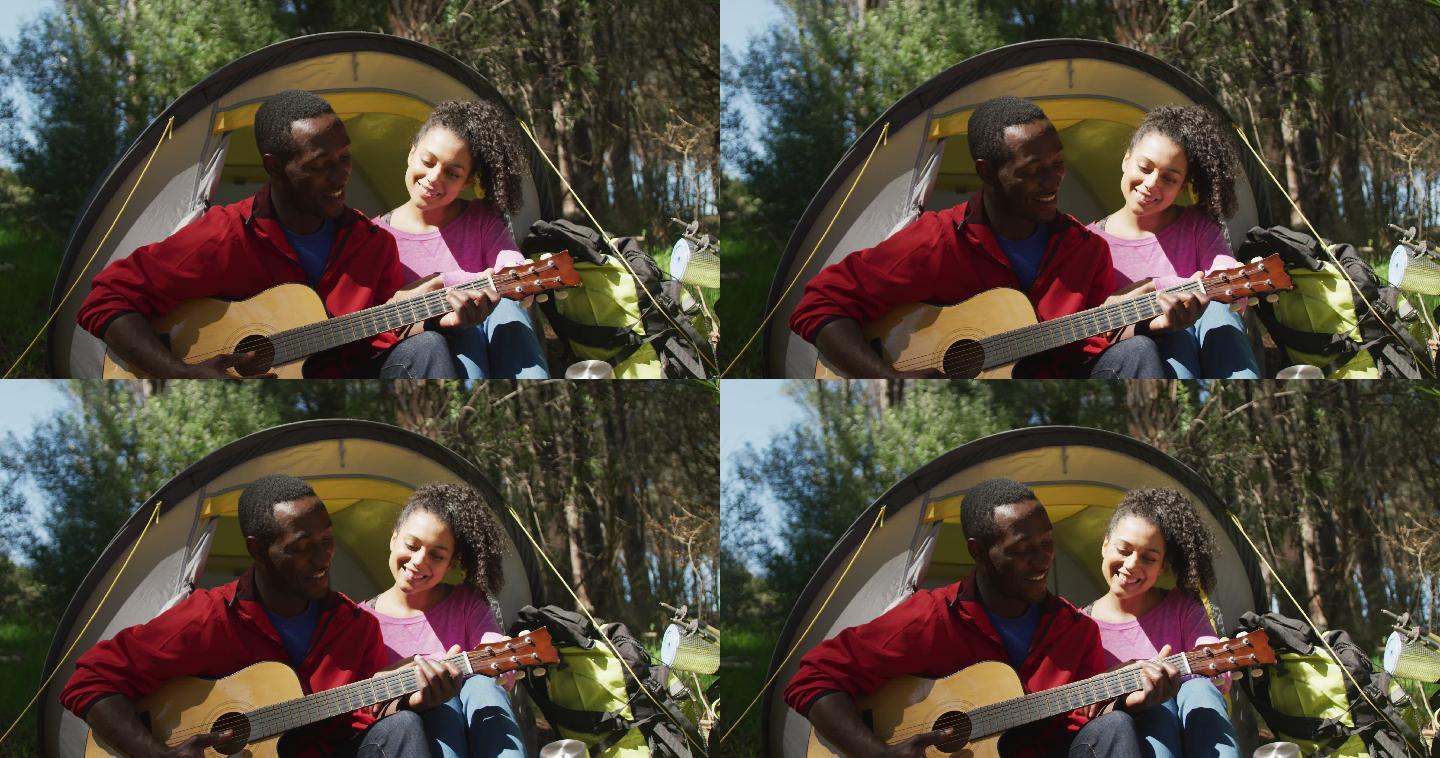 微笑的夫妇坐在帐篷和吉他在乡下