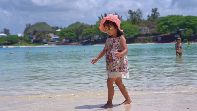 可爱的小女孩在海边沙滩走路