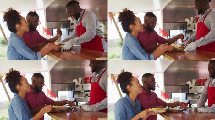 面带微笑的非洲裔美国男性餐车主人为快乐的多样化夫妇提供食物