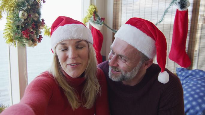 幸福的白种成熟夫妇在满是圣诞装饰的房间里视频通话