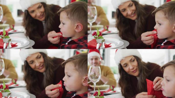 快乐的白人母亲在圣诞餐桌上给儿子擦嘴