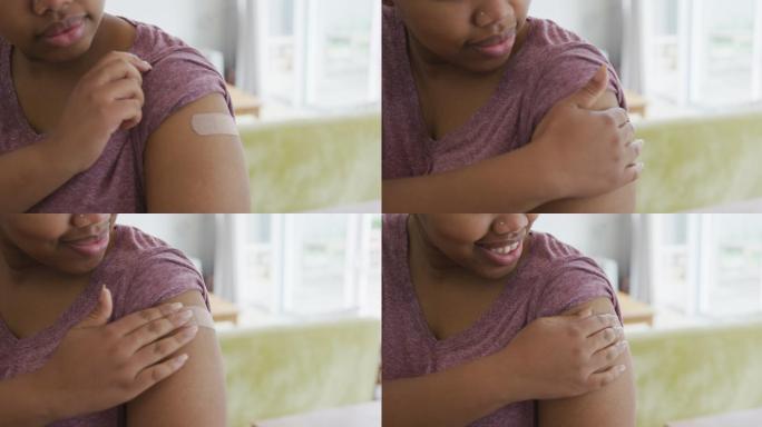 快乐的非洲裔美国妇女在接种疫苗后手臂上缠着绷带