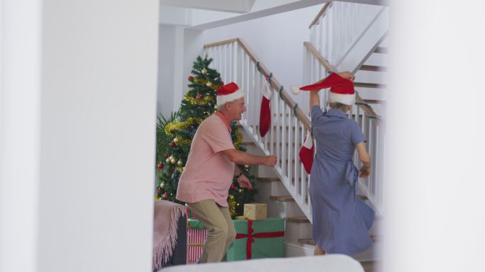 快乐的白种人老夫妇戴着圣诞帽，在圣诞节跳舞