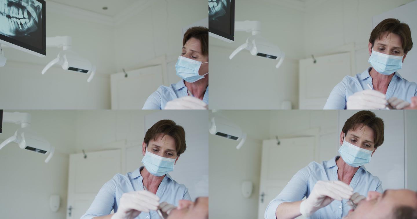 戴口罩的白人女牙科护士在现代牙科诊所检查男性病人的牙齿