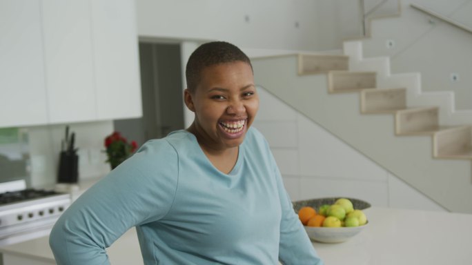微笑的非裔美国胖女人的肖像看着厨房里的相机