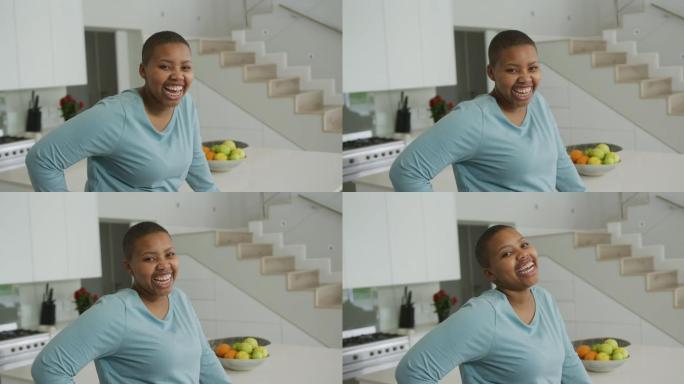 微笑的非裔美国胖女人的肖像看着厨房里的相机
