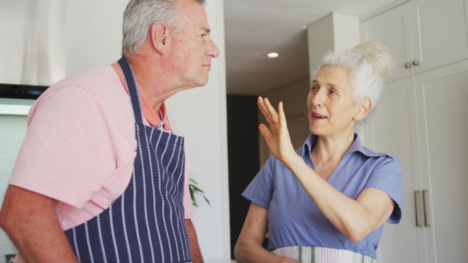 快乐的白种人老夫妇穿着围裙一起在厨房做饭