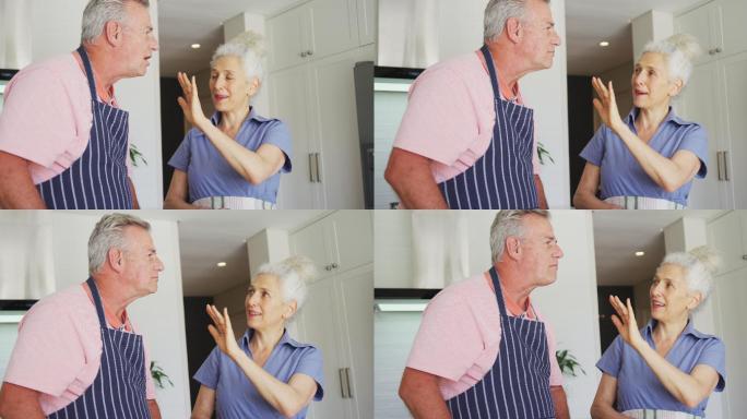 快乐的白种人老夫妇穿着围裙一起在厨房做饭