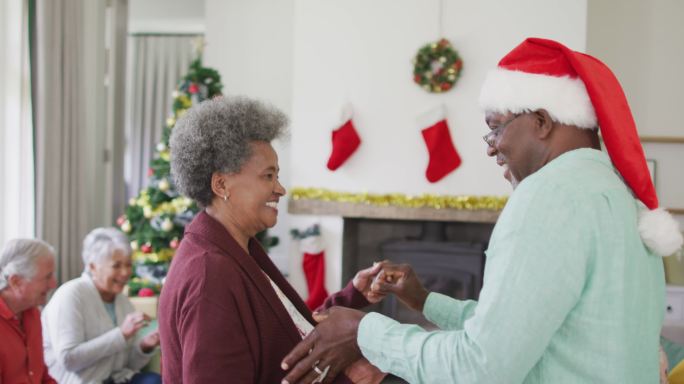 快乐的非裔美国老年夫妇和朋友在圣诞期间一起跳舞