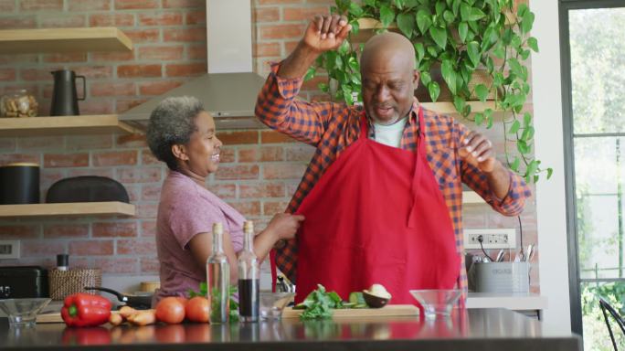 快乐的非裔美国老夫妇在厨房里一起做饭