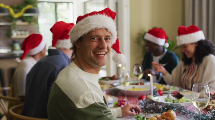 快乐的白人男子在圣诞期间与朋友庆祝晚餐