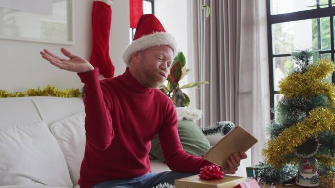 快乐的白化病非裔美国人戴着圣诞老人帽在圣诞节进行视频通话
