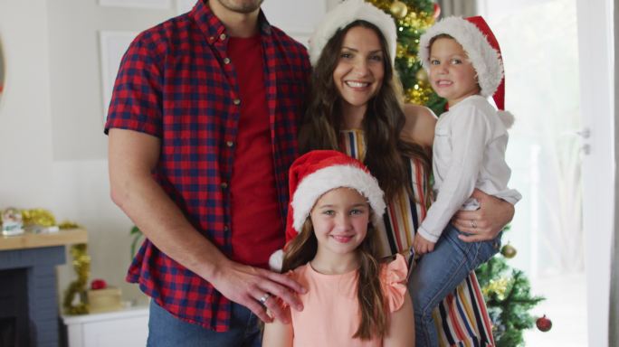 幸福的白人家庭戴着圣诞帽看着镜头