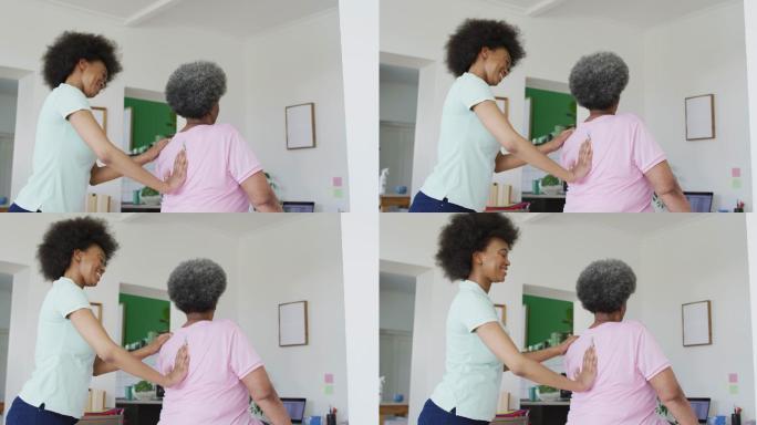 非裔美国女性理疗师戴着口罩帮助老年女性病人锻炼