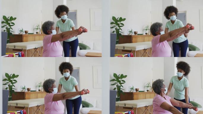 非裔美国女性理疗师戴着口罩帮助老年女性病人锻炼