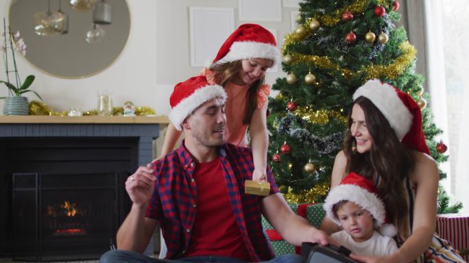 快乐的白人家庭戴着圣诞帽分享礼物