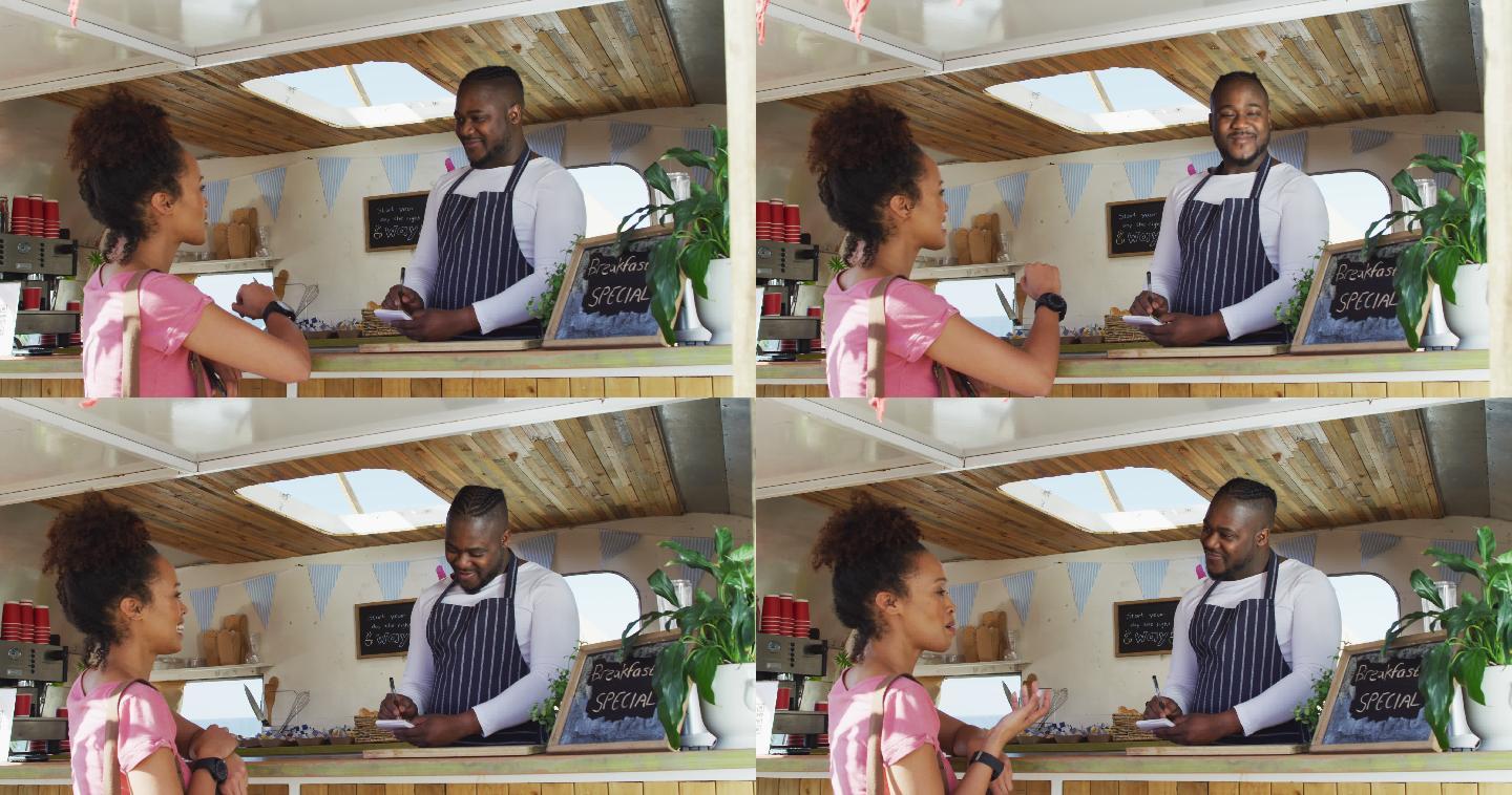 微笑的非洲裔美国男性餐车老板接受快乐的女性顾客的订单