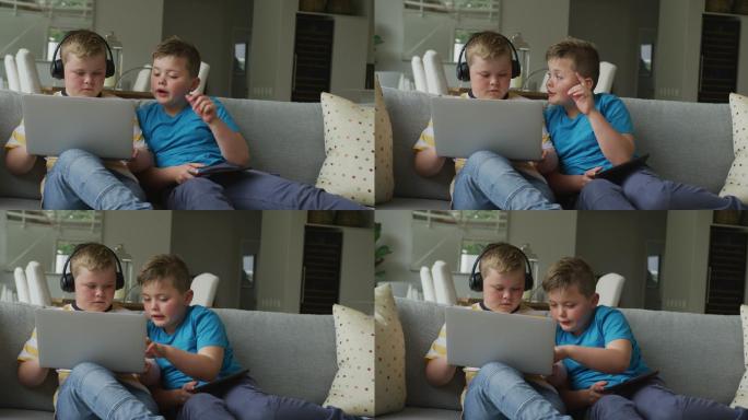 一个白人男孩和他哥哥坐在客厅里用笔记本电脑
