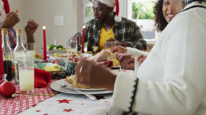 快乐的非裔美国人多代家庭戴着圣诞帽，庆祝节日大餐