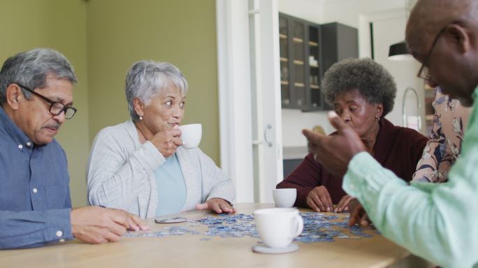 一群快乐的不同年龄的朋友在家里喝咖啡，玩拼图