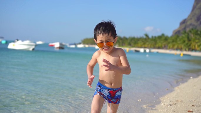 海边沙滩欢快奔跑的小男孩