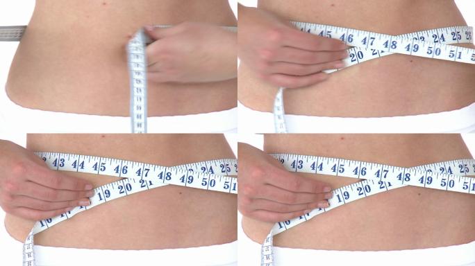 妇女用卷尺测量自己的腰特写