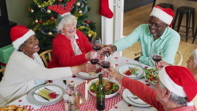快乐的一群不同的老年朋友在圣诞期间庆祝大餐和喝葡萄藤