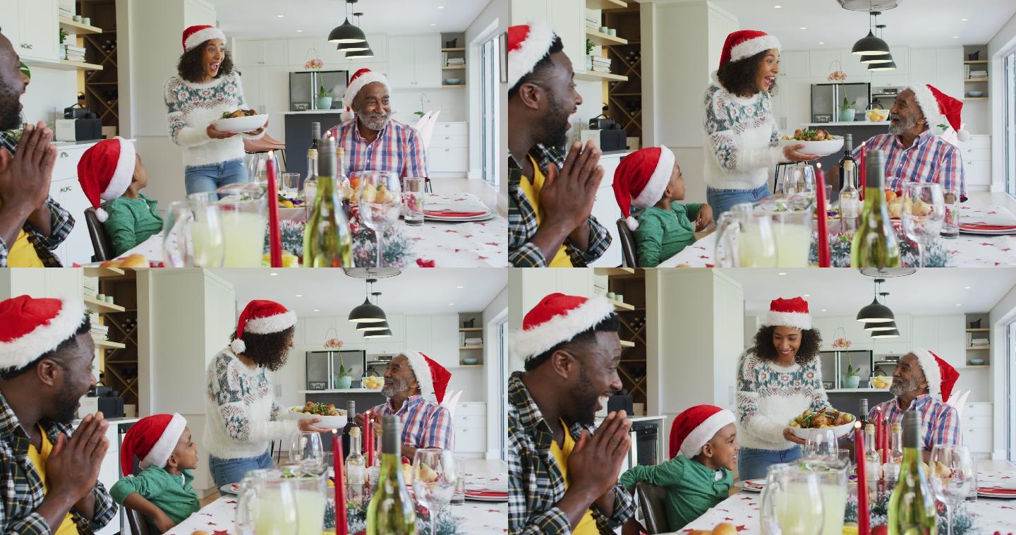 快乐的非裔美国人多代家庭戴着圣诞帽在厨房庆祝