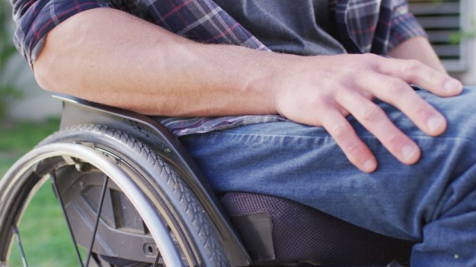 白人残疾人在街上坐轮椅的特写