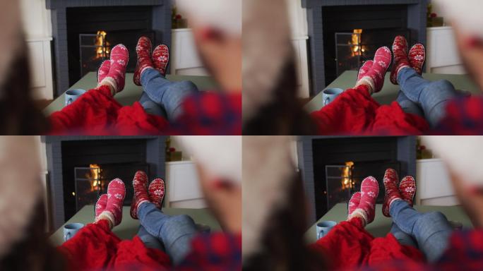 一对白种人夫妇的脚坐在沙发上，穿着圣诞袜，戴着圣诞帽