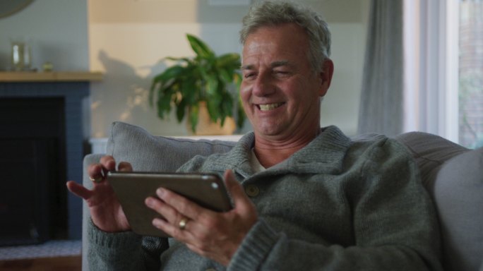 快乐的白人老人在家里用智能手机