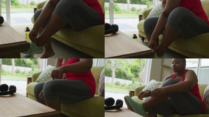 快乐的非裔美国胖女人在客厅练瑜伽，穿鞋