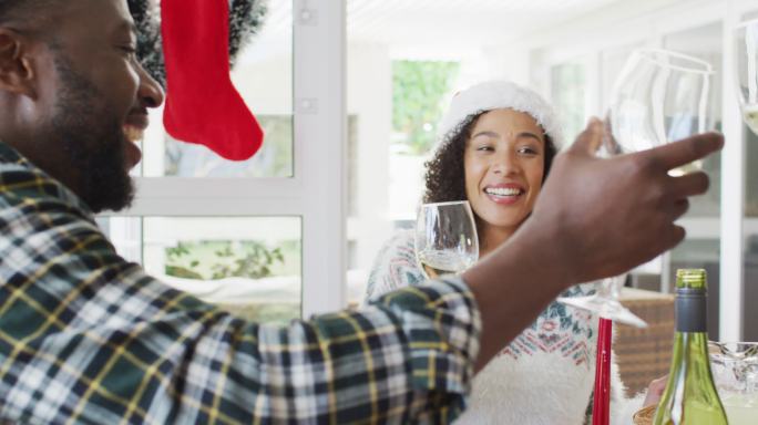 快乐的非裔美国夫妇戴着圣诞帽在厨房庆祝