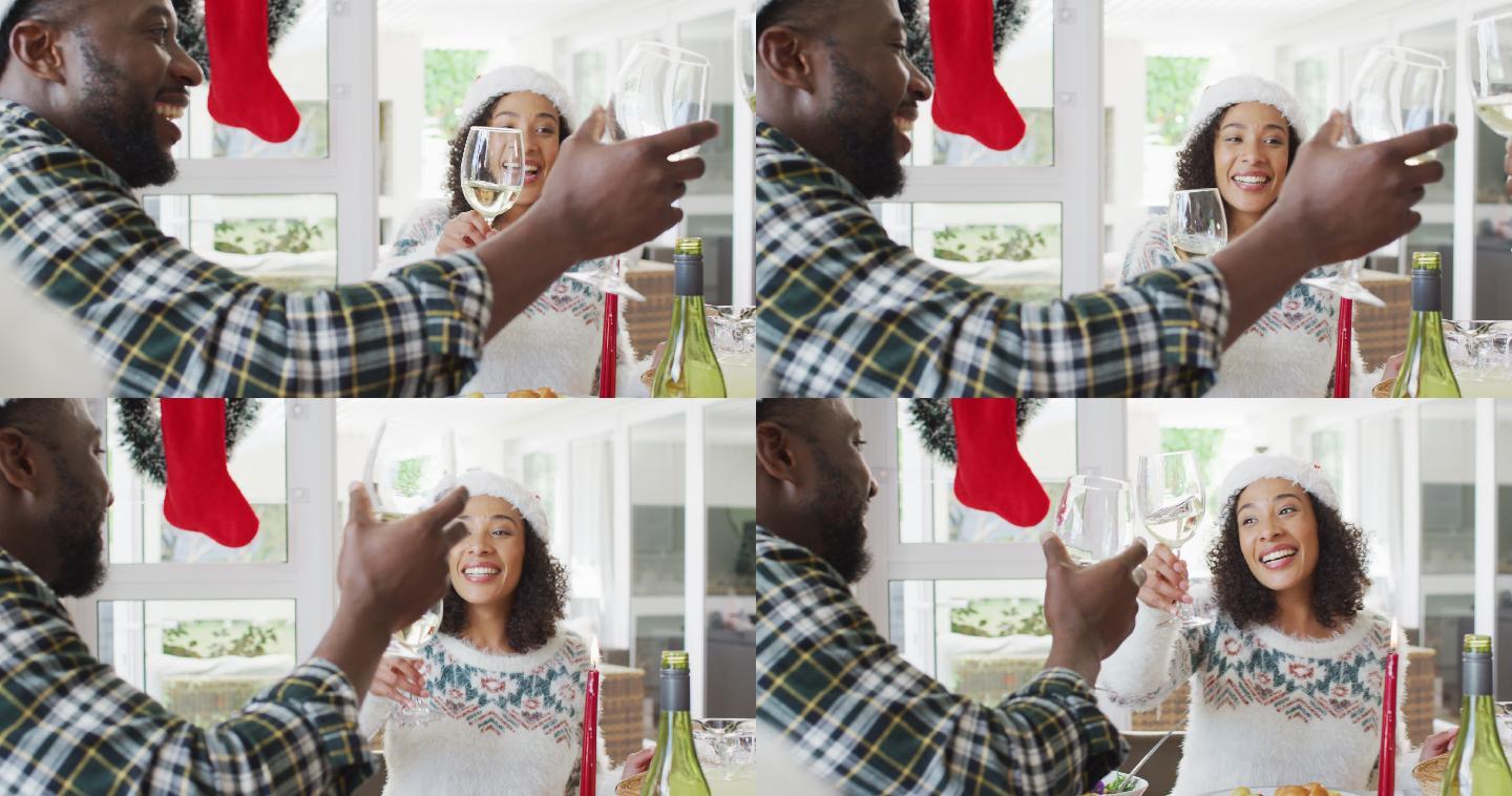 快乐的非裔美国夫妇戴着圣诞帽在厨房庆祝