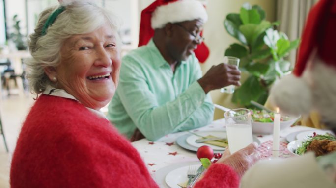 快乐的白人老年妇女庆祝晚餐与朋友在圣诞节时间