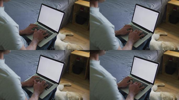 白人男子在卧室用笔记本电脑和宠物狗