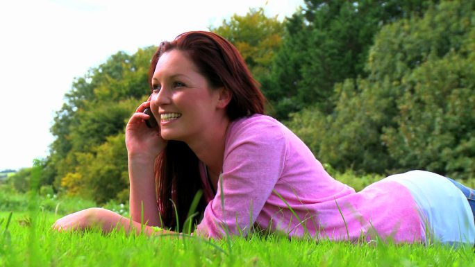 一个女人躺在草地上打电话特写